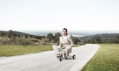 Beautiful young woman riding children's bicycle