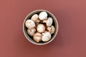 mushrooms in a bowl top view against brown background
