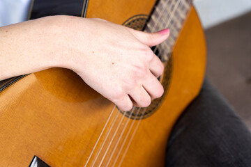 Crop female guitarist touching strings of guitar