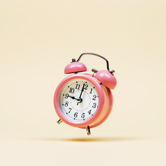The pink alarm clock is levitate in the air, against a yellow background. The concept of time, copy...