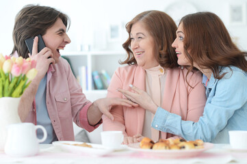 happy family of three spending time together at dinner table with cookies and tea