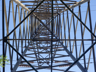 Close up of power poles and towers in the background of blue sky