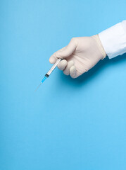 hands in medical gloves with a syringe on a blue background, imitation of a coronavirus vaccine, prevention of infection with viruses and bacteria