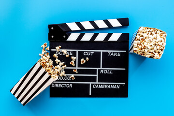 Popcorn with clapperboard and movie film reel. Cinema background