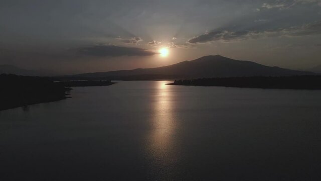 Aerial view of a beautiful sunset on a lake near a mountain with an incredible reflection of the sun.