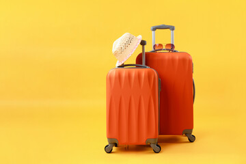 Two suitcases of travel bags, straw hat and sunglasses on yellow background with copy space....