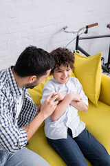 young arabian man tickling cheerful son while having fun at home