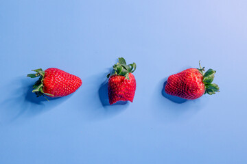 Background composed of three strawberries, one of which is bitten with an infinite blue background
