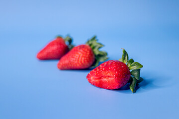 Background composed of three strawberries, one of which is bitten with an infinite blue background
