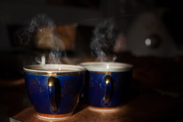 Cups of green tea in a beautiful cup. Retro style. A mug of tea with spectacular smoke. Wooden background. 