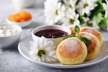 Obraz na płótnie Canvas Aromatic vanilla cheesecakes with raspberry jam and sour cream for breakfast 