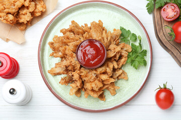 Delicious onion blossom with ketchup served on white wooden table, flat lay