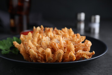 Delicious onion blossom served on black table, closeup