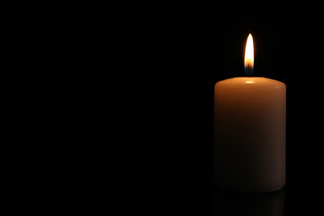 Fototapeta na wymiar Burning candle on dark background, space for text. Memory day