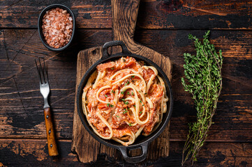 Trendy baked Feta pasta with Oven roasted tomatoes and cheese in a pan. Dark wooden background. Top...