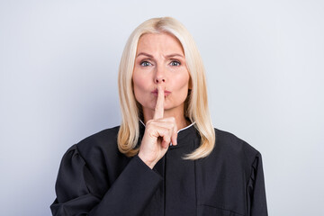 Portrait of attractive clever serious woman judge showing shh sign dont speak isolated over grey...