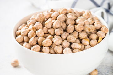 Chickpeas in white bowl at light kitchen table.