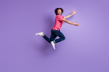 Full length photo of crazy funny young guy dressed pink outfit jumping open arms isolated purple color background