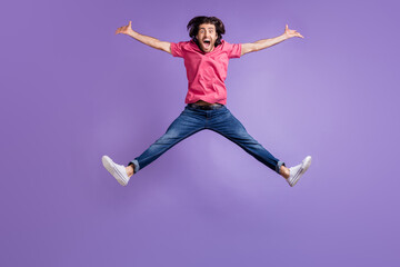 Fototapeta na wymiar Full length photo of funny sportive young man wear pink t-shirt jumping like star isolated violet color background