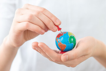 A small globe in hands which point to the chosen place for travel