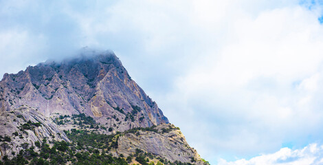 Mountain in the clouds. Cloudy sky and high cliff.
