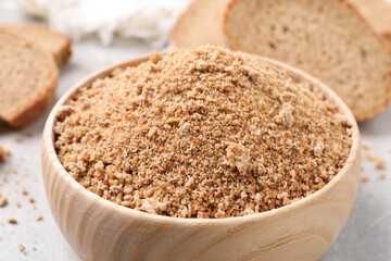 Fresh bread crumbs in bowl on grey table, closeup