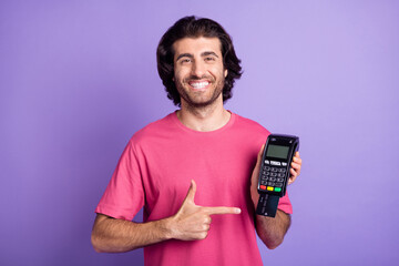 Photo of pretty cute young man wear pink t-shirt pointing finger bank card terminal isolated violet...