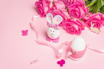 Traditional Easter symbols concept with cute rabbit from an egg, festive decor and gentle roses
