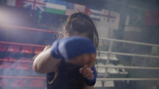 Female boxer performing punching in bandages, accelerated footage