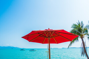 Obraz na płótnie Canvas Red umbrella around sea beach ocean with coconut palm tree