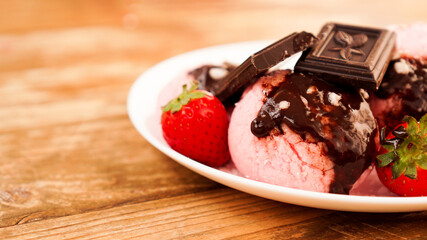 Homemade strawberry ice cream on white plate on a rustic background.
