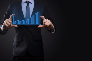 Business man holding holographic graphs and stock market statistics gain profits. Concept of growth planning and business strategy. Display of good economy form digital screen.