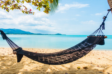 Empty hammock swing around beach sea ocean with white cloud blue sky
