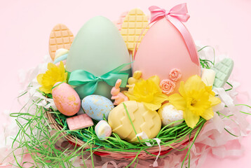 Easter basket full of chocolate eggs and flowers. 