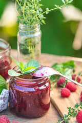 Raspberry jam and fresh raspberry on a rustic wooden table in the garden.