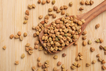 Dried chickpeas in wooden spoon on wooden background.