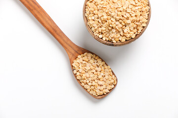 Unpolished Pigeon pea also known as toor dal in a bowl and spoon. Isolated on white background.