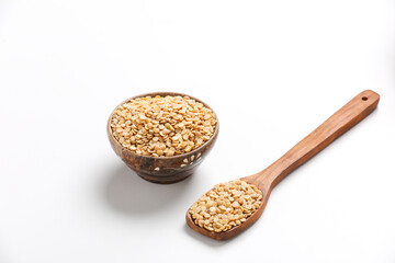 Unpolished Pigeon pea also known as toor dal in a bowl and spoon. Isolated on white background.