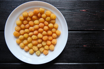 Ripe yellow raspberry lies on a white plate on a black background. Top view. Copy space.