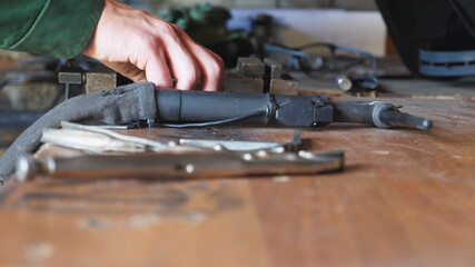 Male hands of repairman using pliers for fixing metal detail on table at workshop. Young mechanic working in garage. Concept of maintenance service. Close up Slow motion
