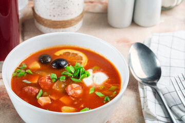 Russian soup Solyanka with smoked meat, sausages, vegetables, pickles and olives with lemon. Traditional Sour Soup