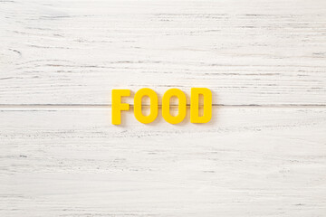 The sign, word food on a white wooden background, top view. Children colored plastic letters