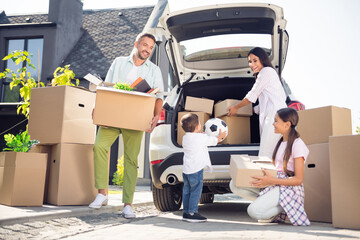 Portrait of nice cheery family owners brother sister moving to new place taking belongings from car credit loan in cottage town outdoor