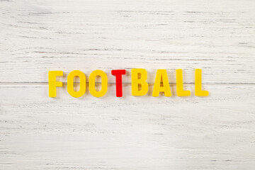 The sign, word football on a white wooden background, top view. Children colored plastic letters, kids sport