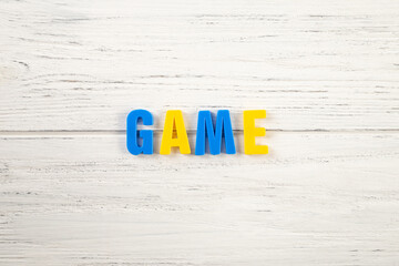 The sign, word game on a white wooden background, top view. Children colored plastic letters