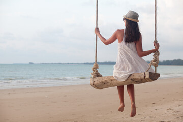 Young Woman swinging at tropical beach in Thailand