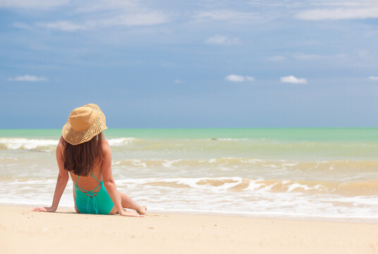 back view of beautiful woman sunbathing on a beach