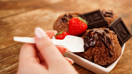 Hand with a spoon. Homemade chocolate ice cream with chocolate and strawberries
