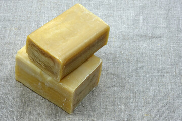 Laundry soap on linen. two pieces of brown natural soap on a gray background. Rectangular laundry soap.