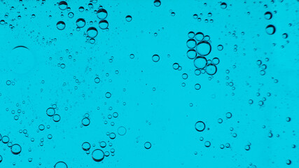 Oil bubbles on the water surface in motion, on a turquoise background, macro, splash screen, template, copy space